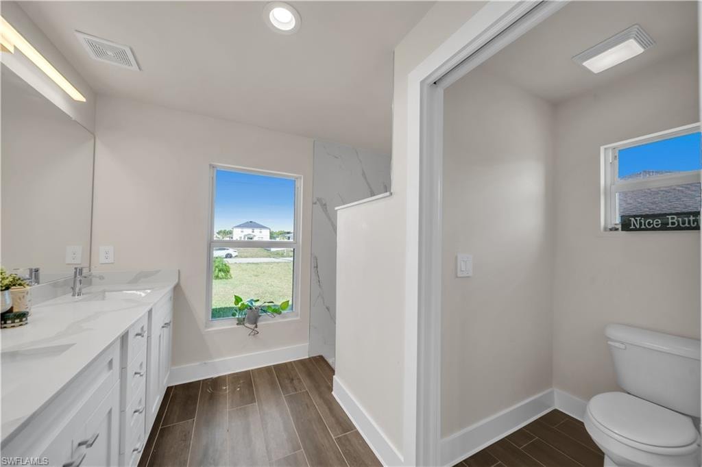 Full bath featuring wood finish floors, double vanity, and a marble finish shower