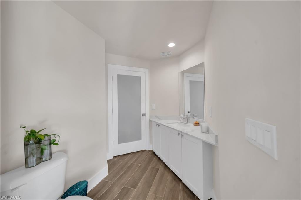 Bathroom featuring wood tiled floors, vanity, and recessed lighting
