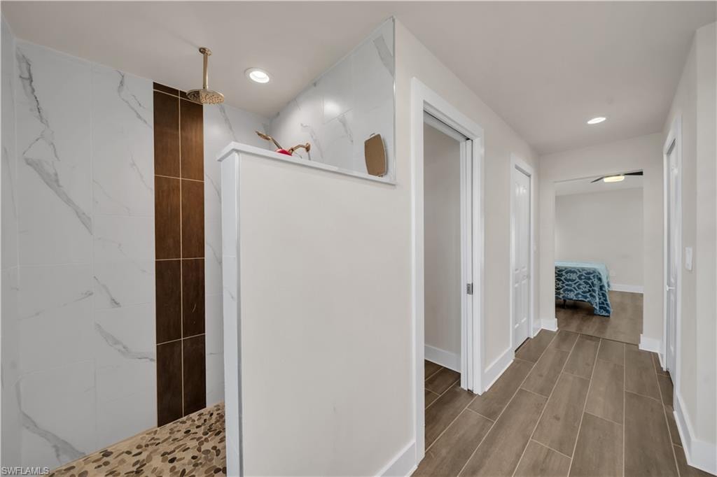 Ensuite bathroom with a marble finish shower, wood finish floors, and recessed lighting