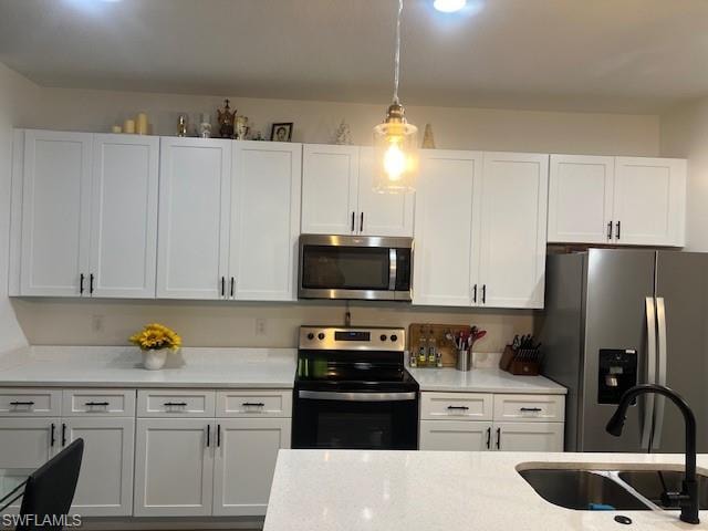 Kitchen with stainless steel appliances, white cabinets, light stone countertops, and pendant lighting