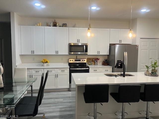 Kitchen with decorative light fixtures, stainless steel appliances, light stone counters, and white cabinetry