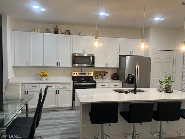 Kitchen with decorative light fixtures, light stone counters, stainless steel appliances, a kitchen bar, and white cabinets