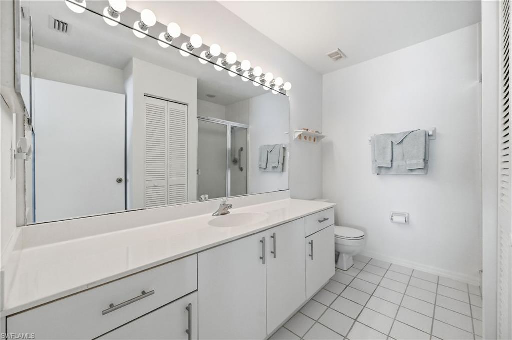 Bathroom with a closet, vanity, a stall shower, and light tile patterned floors