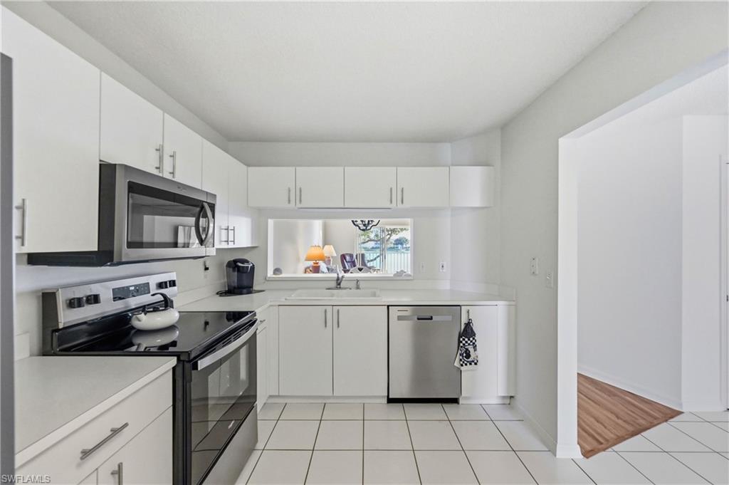 Kitchen featuring stainless steel appliances, light countertops, white cabinets, and light tile patterned floors