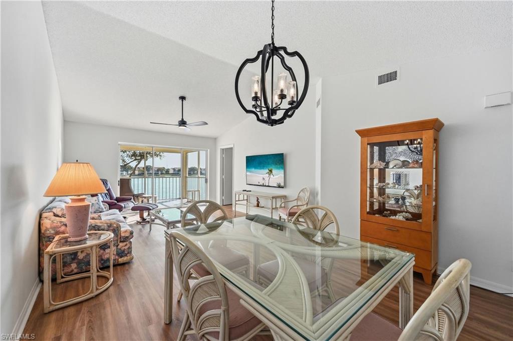 Dining space with hanging lights, dark wood-style floors, a ceiling fan, and vaulted ceiling