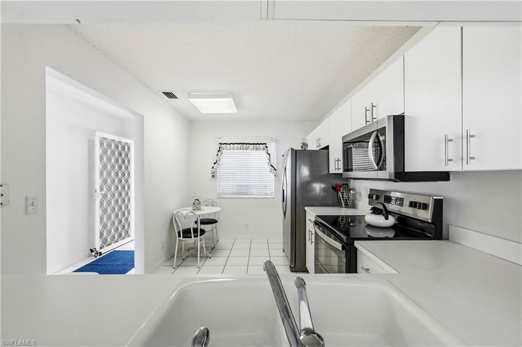 Kitchen featuring stainless steel appliances, light countertops, white cabinetry, and light tile patterned floors