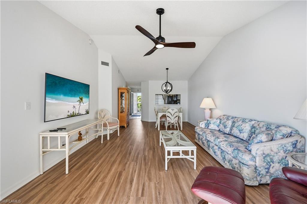 Living room with wood finished floors, lofted ceiling, and ceiling fan