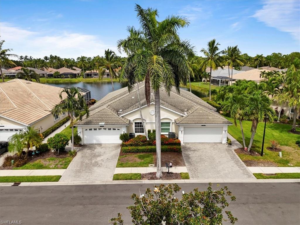 Mediterranean / spanish-style home with decorative driveway, a water view, a tile roof, stucco siding, and a residential view