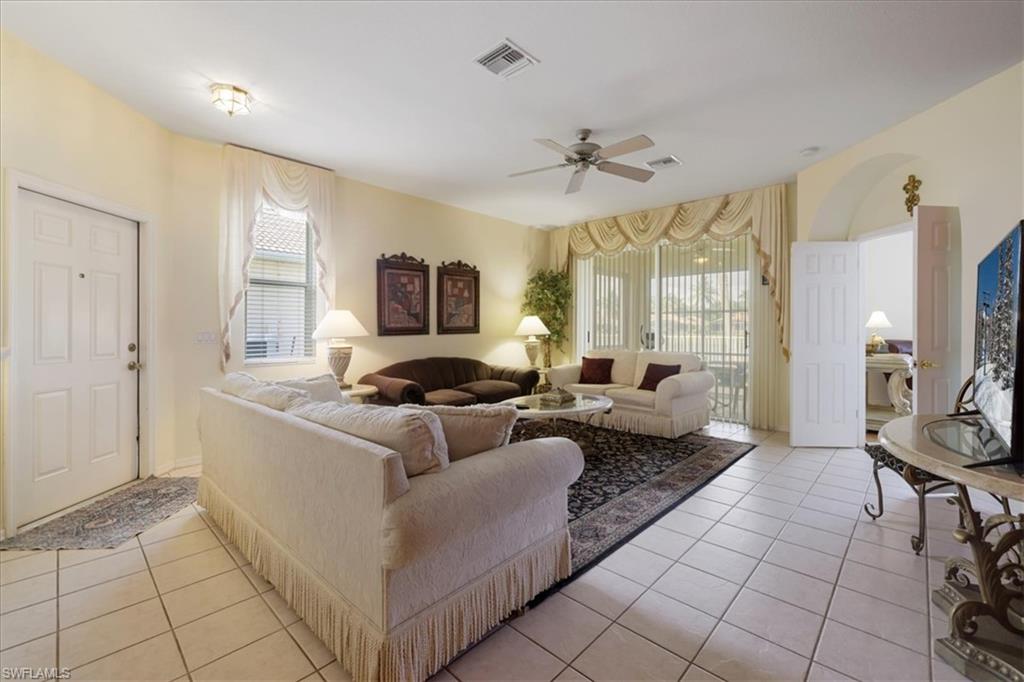 Living area featuring light tile patterned floors, ceiling fan, and arched walkways