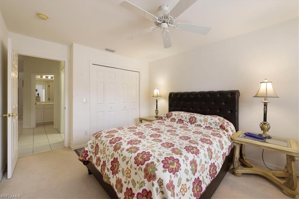 Bedroom with a closet, a ceiling fan, and light carpet