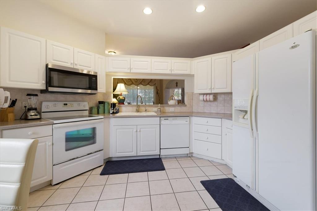 Kitchen featuring white appliances, white cabinets, light countertops, light tile patterned floors, and recessed lighting