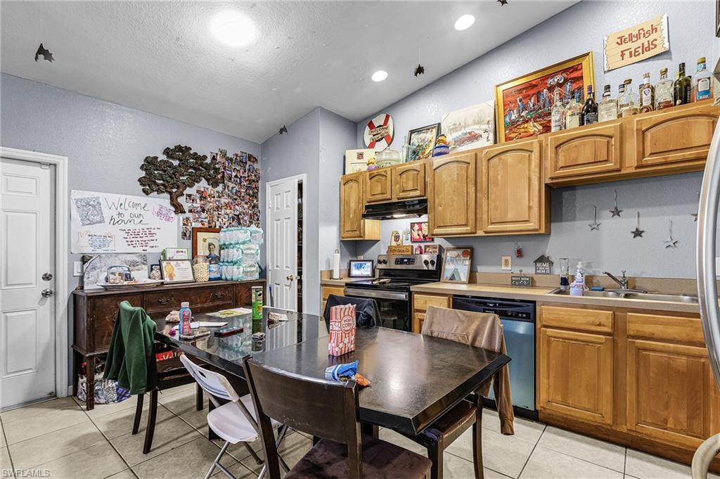 Kitchen with light countertops, stainless steel appliances, light tile patterned floors, and wood finish cabinets