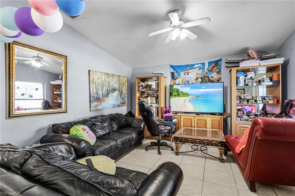 Living area with a ceiling fan, lofted ceiling, and tile patterned floors