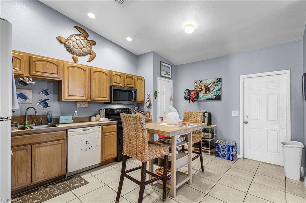 Kitchen featuring dishwasher, light tile patterned floors, stainless steel microwave, light countertops, and electric range