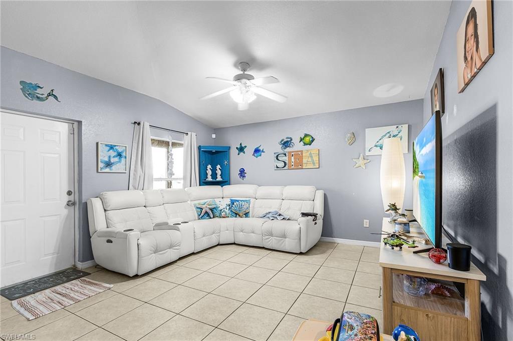 Living area with vaulted ceiling, ceiling fan, and light tile patterned floors