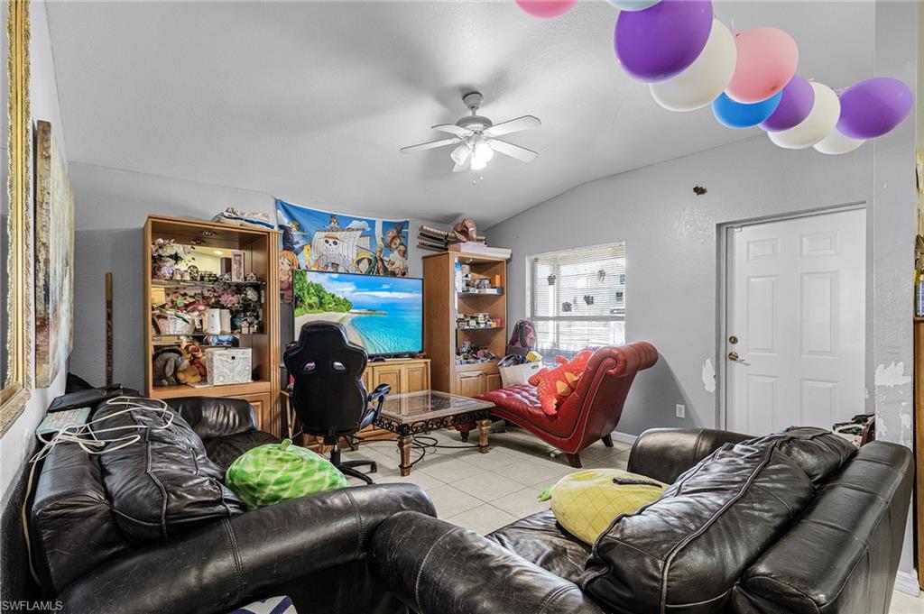 Living room featuring vaulted ceiling, tile patterned flooring, and ceiling fan