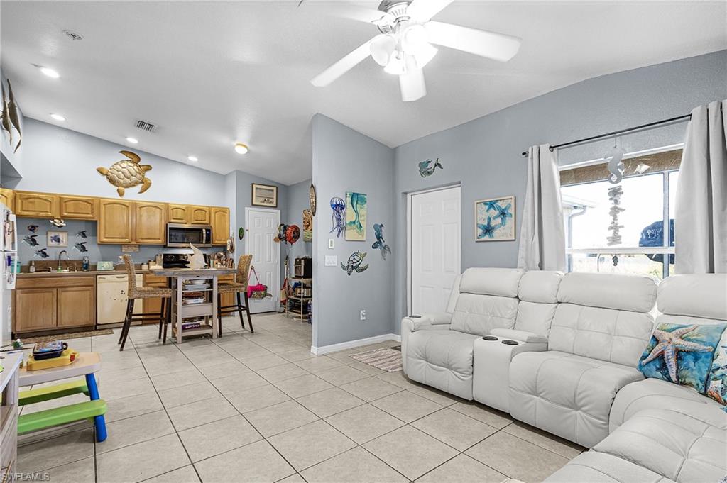 Living area featuring lofted ceiling, ceiling fan, and light tile patterned flooring