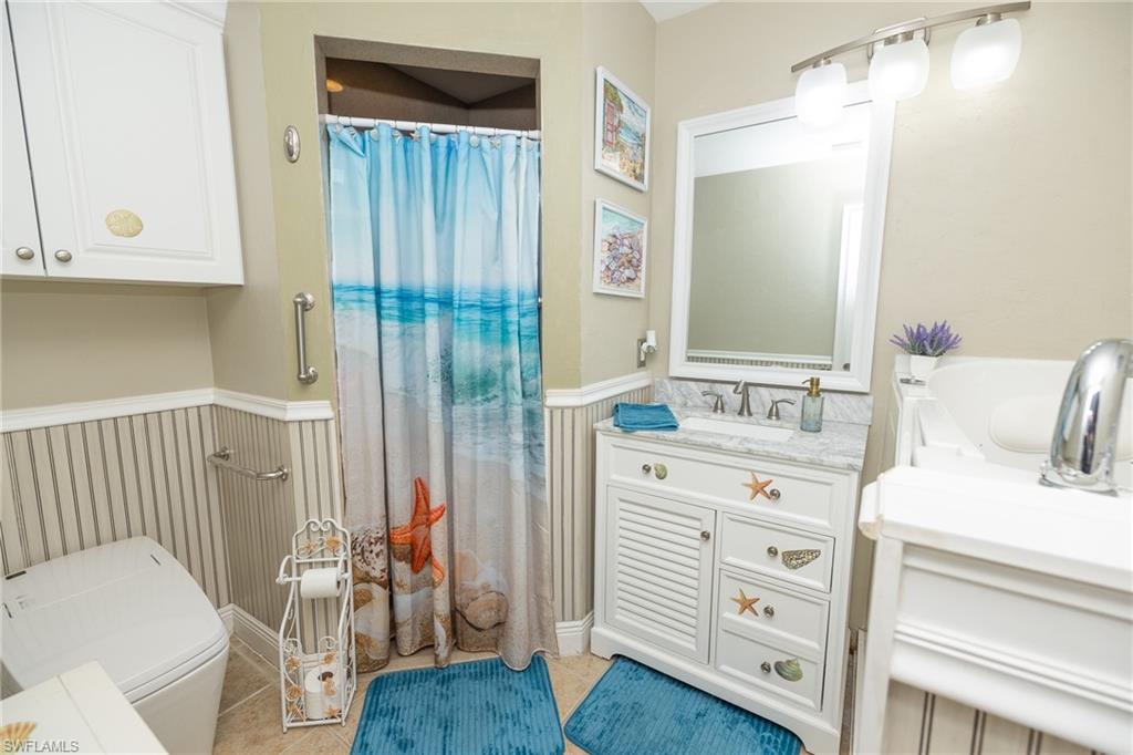 Bathroom with a shower with curtain, vanity, and wainscoting