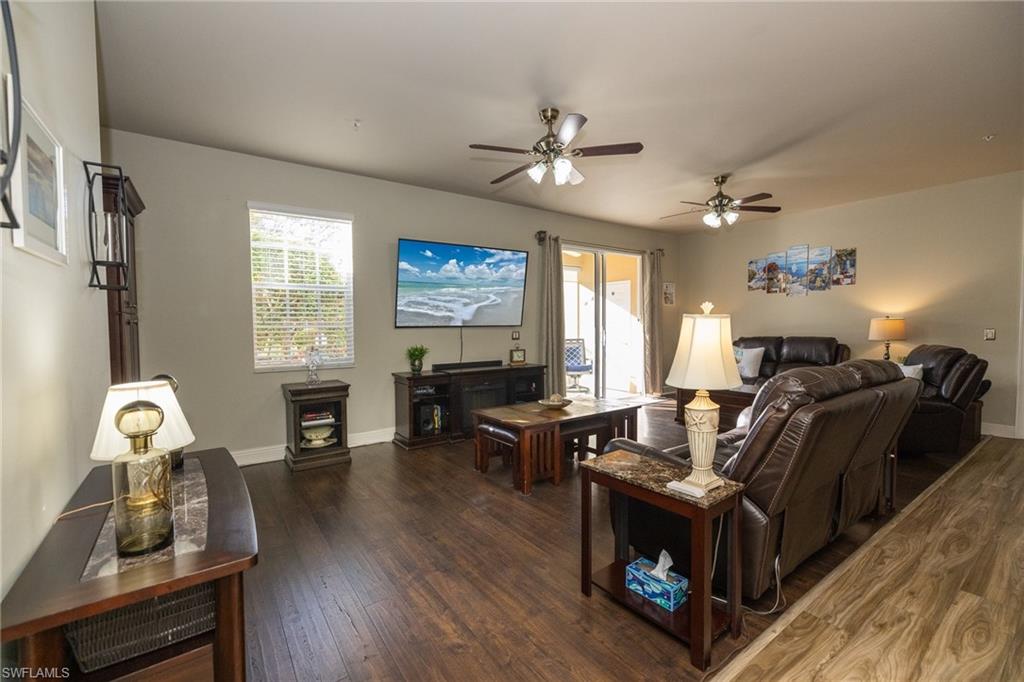 Living room with dark wood finished floors, ceiling fan, and plenty of natural light