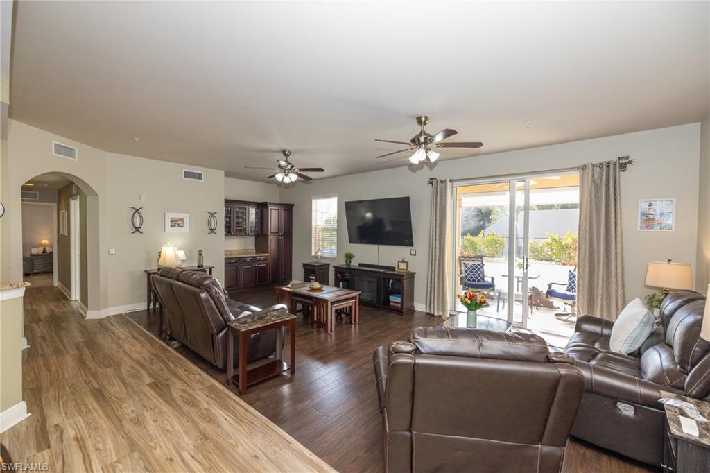 Living area featuring arched walkways, dark wood finished floors, and a ceiling fan