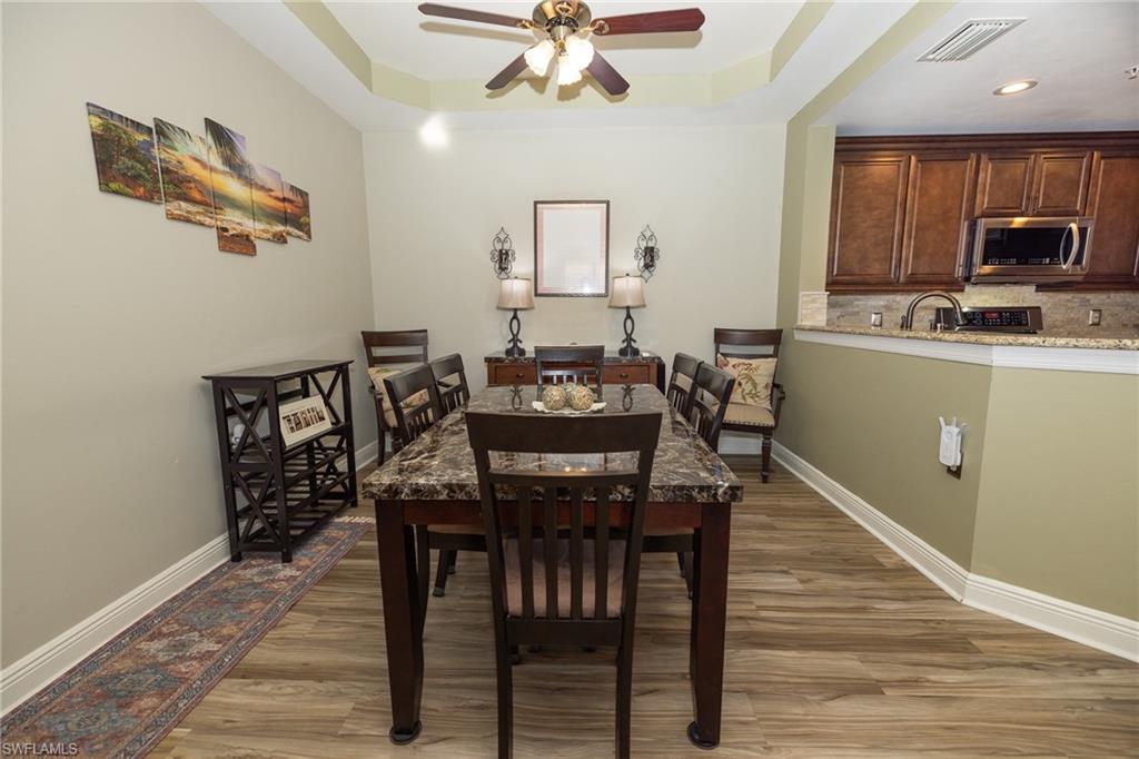 Dining room featuring light wood-style floors, a raised ceiling, and a ceiling fan