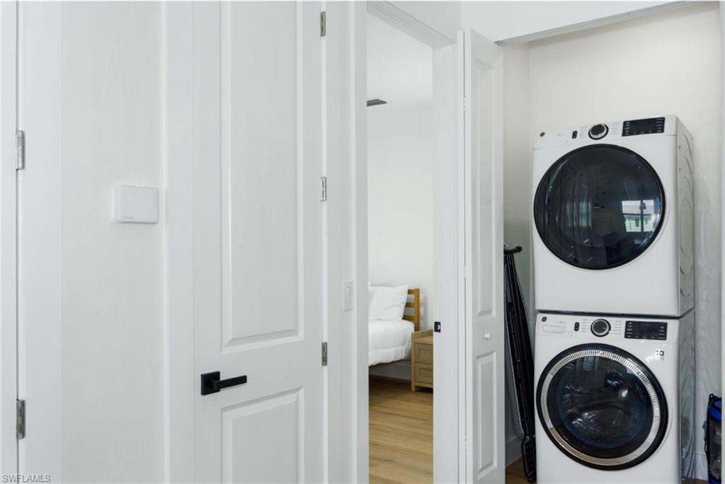 Laundry room with estacked washer and dryer and wood finished floors - Virtually Edited Image