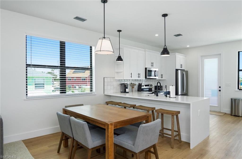 Dining room with light wood-style floors and recessed lighting - Virtually Edited Image