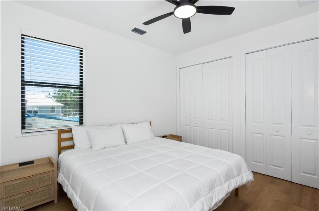 Bedroom with two closets, dark wood  - Virtually Edited Imagefinished floors, and ceiling fan