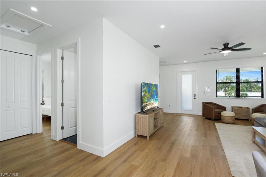 Living room with recessed lighting, light wood-style floors, a ceiling fan, and attic access - Virtually Edited Image