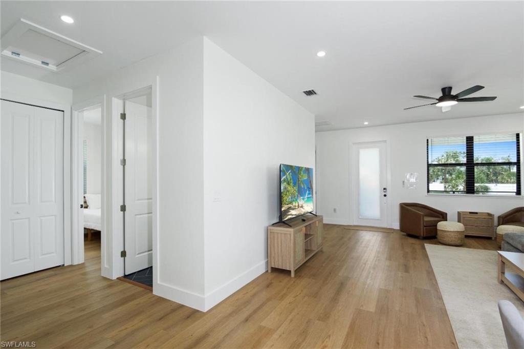 Living room featuring recessed lighting, light wood-style floors, a ceiling fan, and attic access - Virtually Edited Image