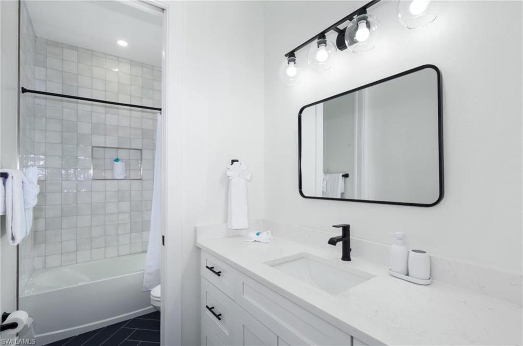 Full bathroom featuring shower / tub combo, vanity, and dark tile patterned floors
