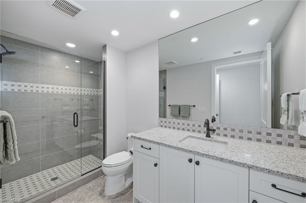 Full bathroom featuring recessed lighting, vanity, a stall shower, and decorative backsplash
