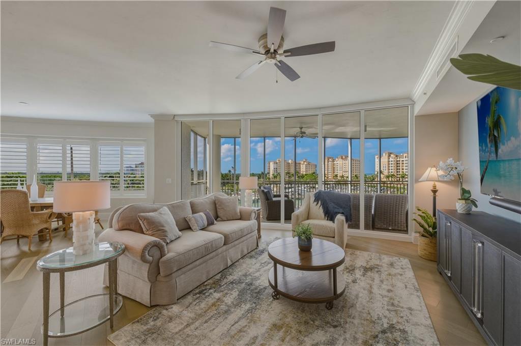 Living room with ornamental molding, light wood finished floors, ceiling fan, and floor to ceiling windows