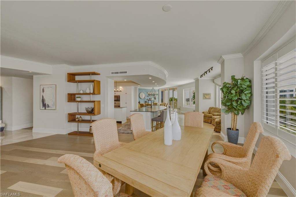 Dining space featuring light wood-type flooring, ornamental molding, and hanging lights