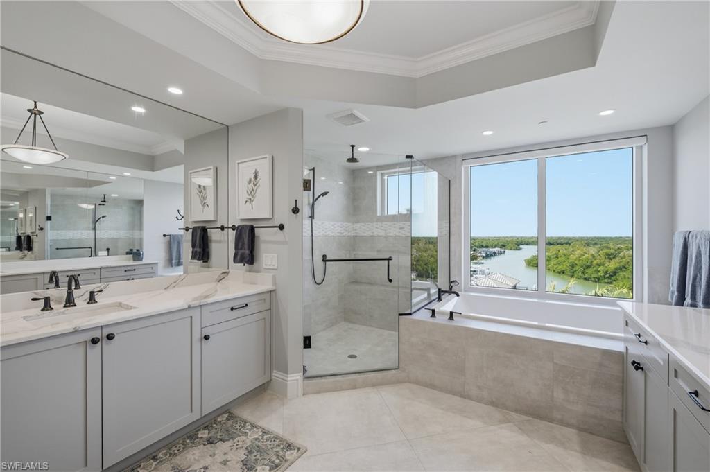 Full bath featuring vanity, ornamental molding, a garden tub, a stall shower, and a water view
