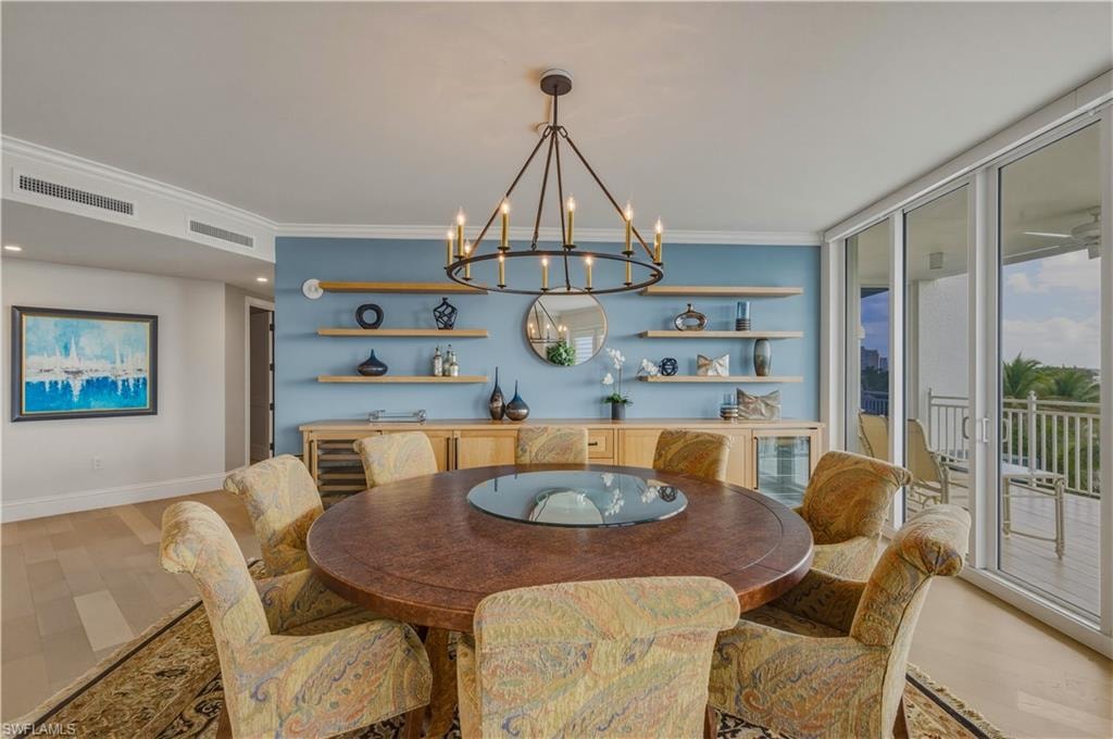 Dining room with light wood-style flooring, hanging lights, ornamental molding, and floor to ceiling windows