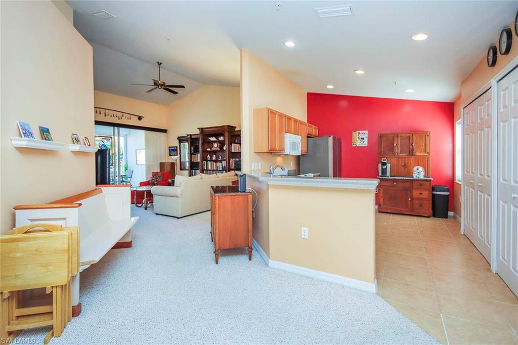 Kitchen featuring light carpet, vaulted ceiling, ceiling fan, open floor plan, and freestanding refrigerator