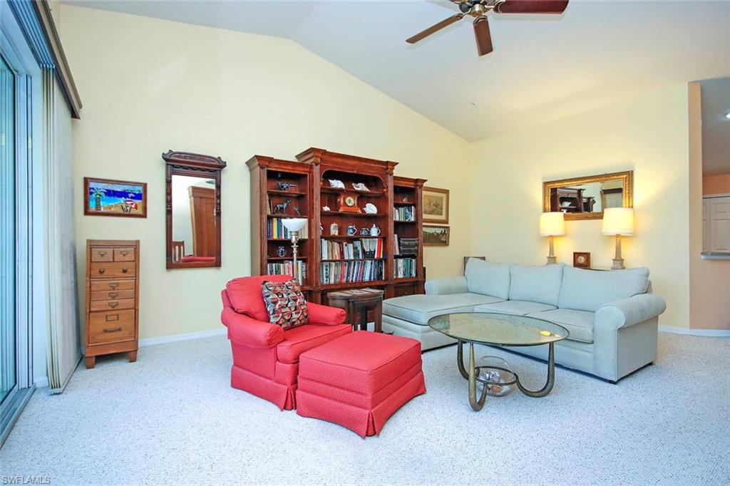 Living room featuring a ceiling fan, vaulted ceiling, and carpet floors