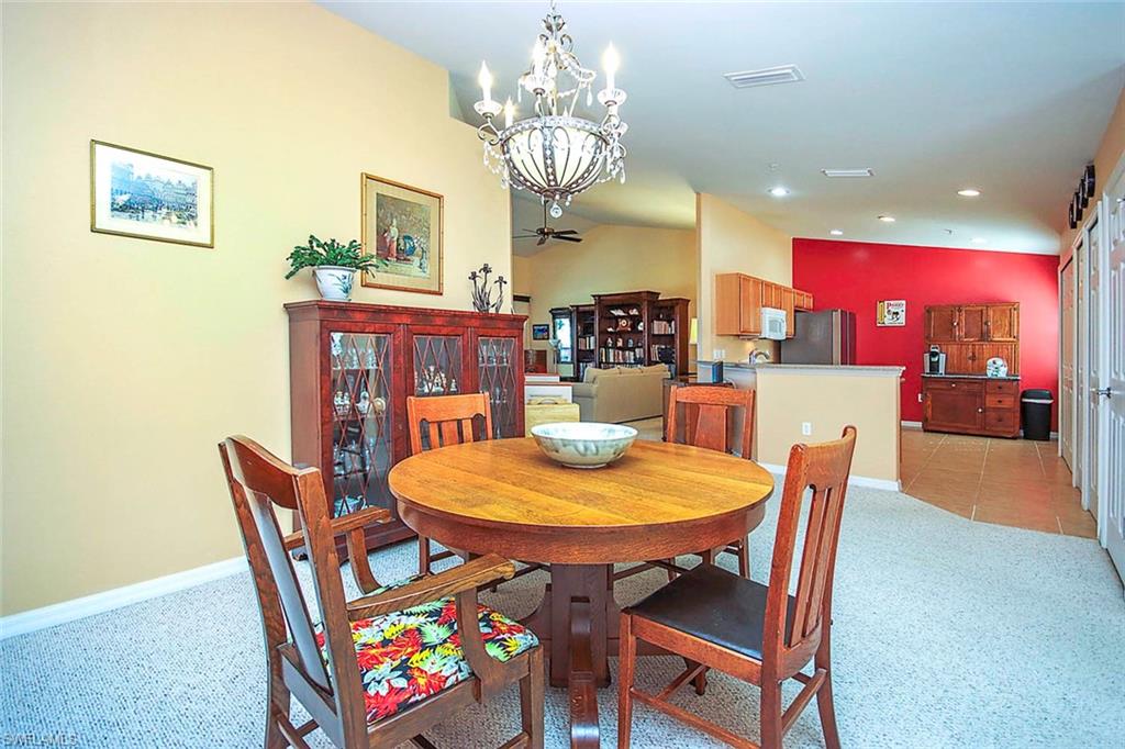 Dining area featuring light carpet, hanging lights, and vaulted ceiling