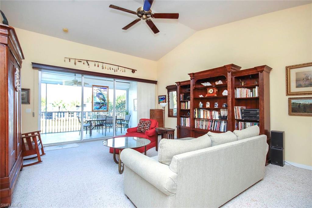 Carpeted living room with ceiling fan, lofted ceiling, and a sunroom