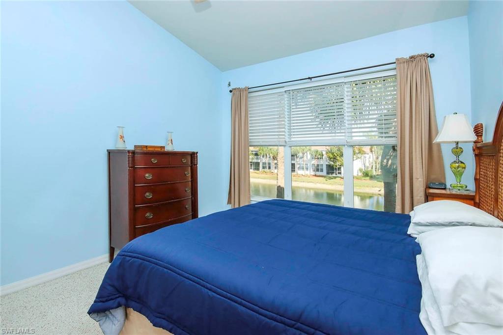 Carpeted bedroom with access to outside, a water view, and vaulted ceiling