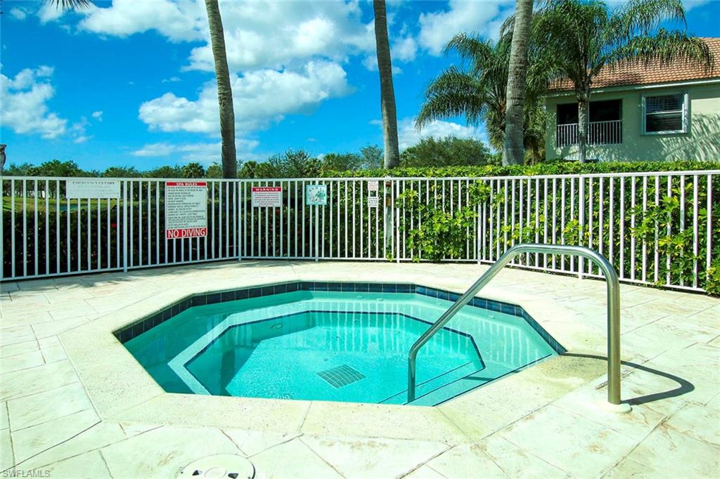 View of spa next to the swimming pool featuring a hot tub and patio surround