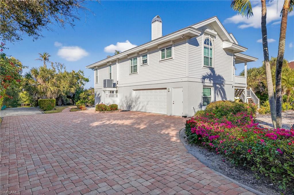 View of home's exterior with an attached garage, stucco siding, decorative driveway, and a chimney