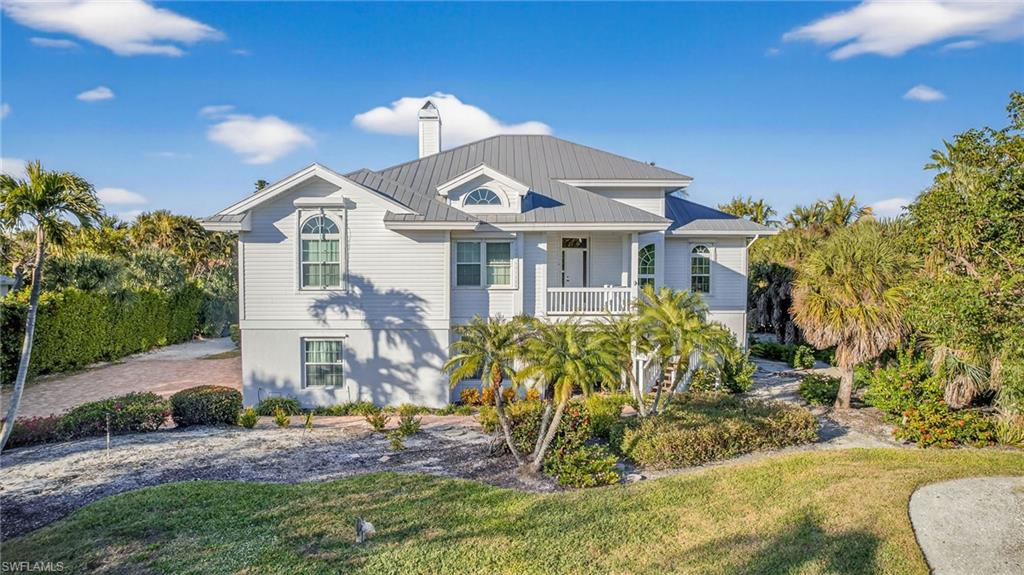 Raised beach house with a chimney, a front lawn, and a metal roof