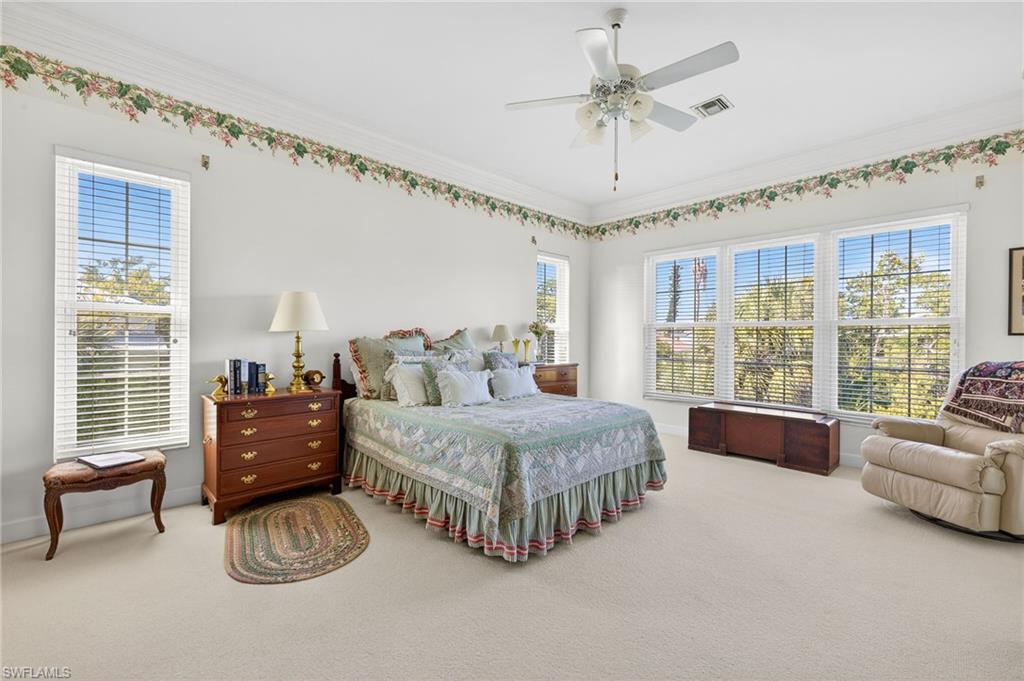 Carpeted bedroom featuring a ceiling fan and crown molding