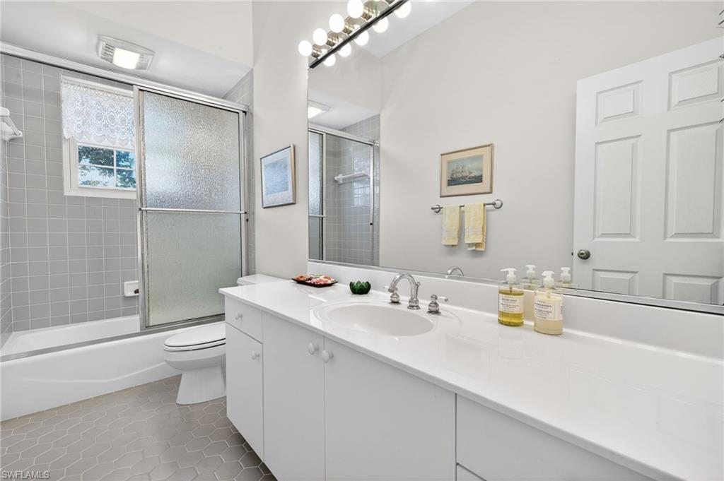 Full bath featuring vanity, light tile patterned floors, and shower / bath combination with glass door