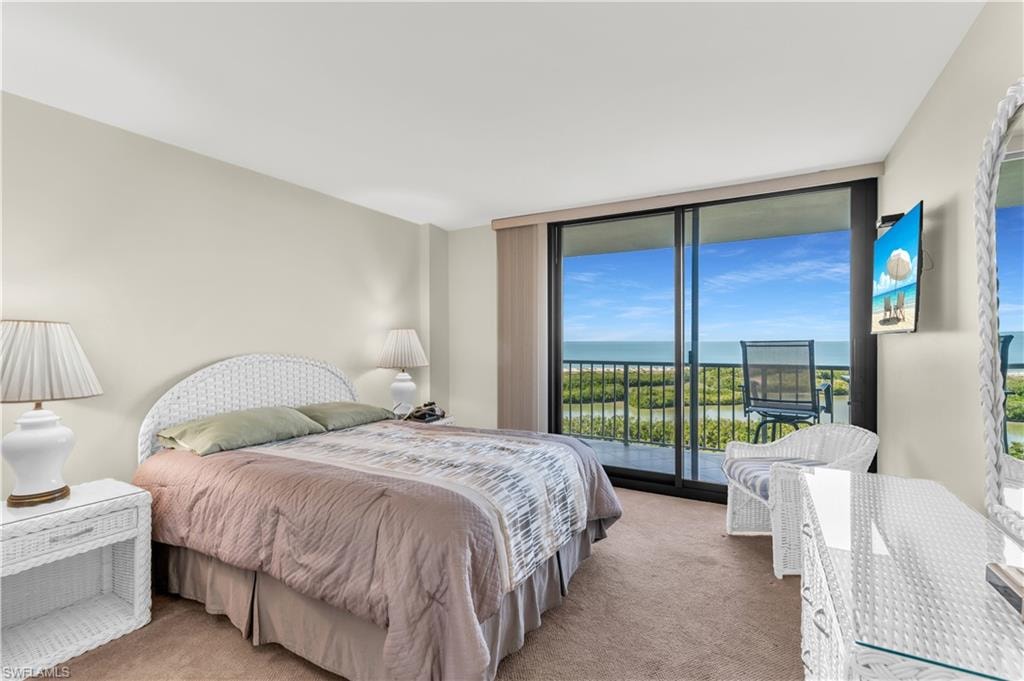 Bedroom with access to exterior, expansive windows, and carpet