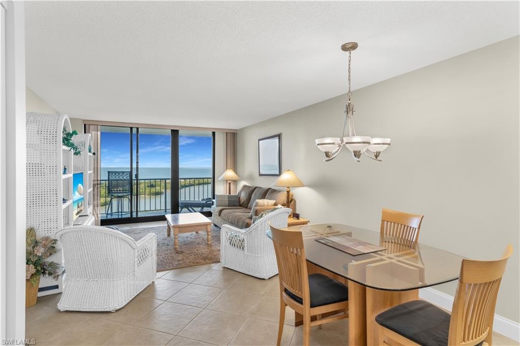 Dining room with a water view, expansive windows, a chandelier, and light tile patterned floors