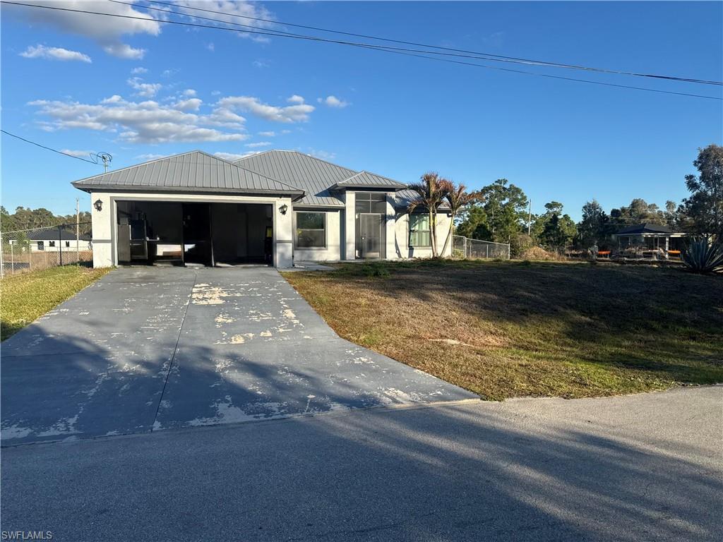 View of front facade with driveway, garage, and a metal roof