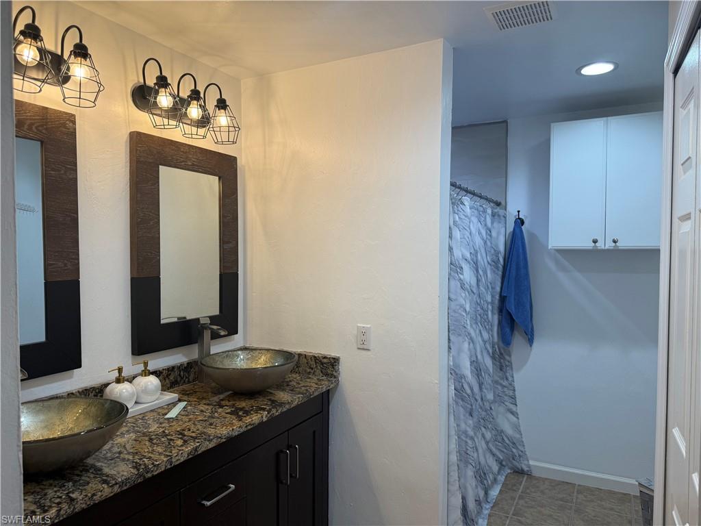 Master bathroom featuring double sink vanity, a shower, recessed lighting, and light tile patterned flooring